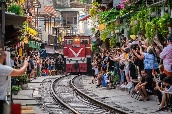 Hanoi Train Street: Zug fährt durch enge Gasse mit Markttreiben