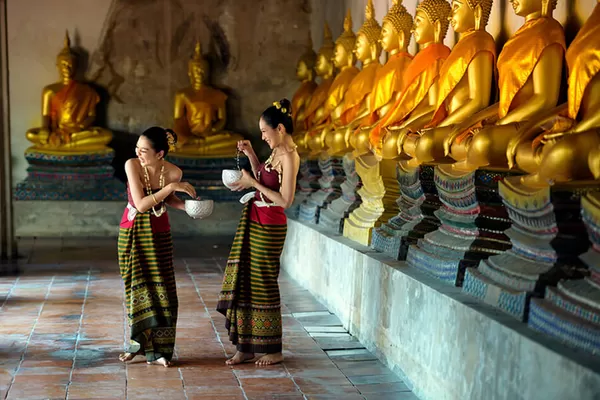 Vergnügte Frauen vor Buddhastatuen im Tempel von Ayutthaya
